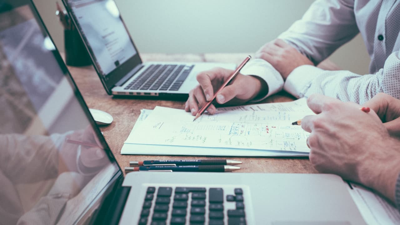 Two people comparing agency options and notes at a desk