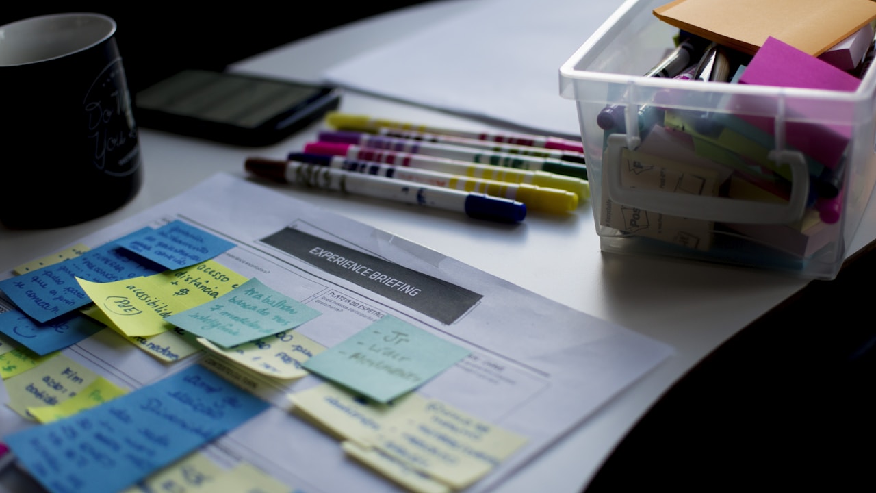Mesa de planejamento com post-its coloridos, canetas e anotações para brainstorming