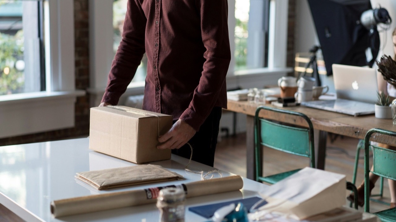 Seller packing a shipping box at a small business workspace