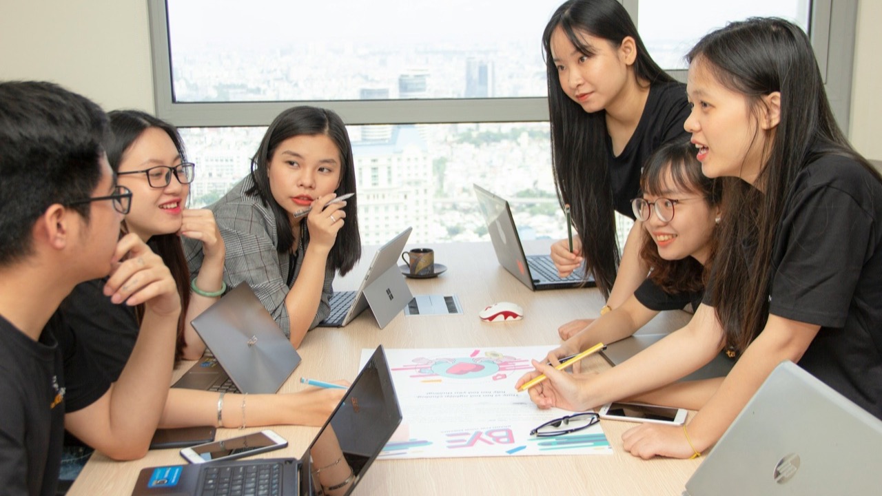 Agency team planning a campaign around a table with laptops